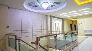A modern interior with a glass railing, a ceiling with a light fixture, and a door in the background. - Cupid Hotel (Palian)