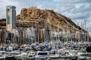 A marina with numerous boats docked, a prominent building labeled "GRAN SOL," and a rocky hill in the background.