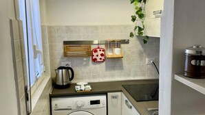 Une cuisine compacte équipée d’un lave-linge, d’une bouilloire et d’une machine à café.