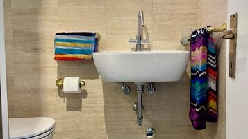 Une salle de bain avec un lavabo blanc, des toilettes et un porte-serviettes orné de serviettes colorées.