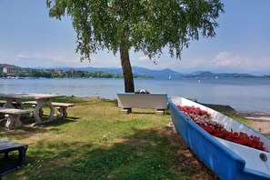 Ein Picknickbereich am Seeufer mit Bänken, einem blumenbepflanzten Beet in Bootsform und einem Picknicktisch.