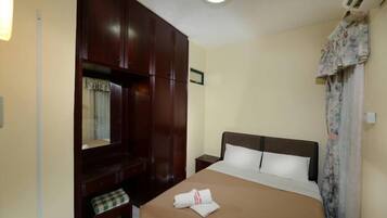 Une chambre d’hôtel avec un lit, une armoire, une petite table et un miroir.
