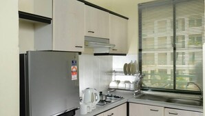 A compact kitchen with a stainless steel refrigerator, a built-in oven, and a sink. - May Condo (Langkawi)