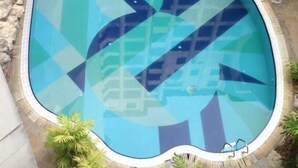 A swimming pool with a geometric tile pattern, surrounded by rocks and small plants. - May Condo (Langkawi)