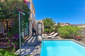 Ein Poolbereich mit freiem Blick auf den Pool, Liegestühle und umliegendes Grün.