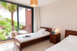 Ein Hotelzimmer mit Bett, Nachttisch und Blick auf Grün hinter einem großen Fenster.