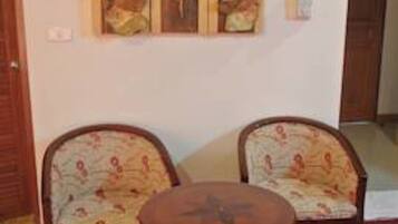 Una habitación con dos sillones tapizados, una mesa redonda de madera y una obra de arte colgada en la pared.