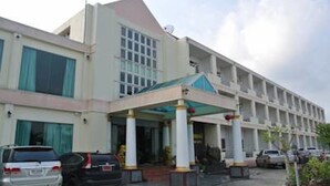 A modern building with a covered entrance, multiple floors, and a parking area with cars. - Chaikanathani Hotel (Phatthalung)