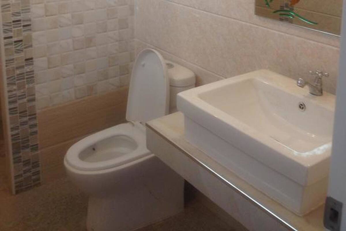 A bathroom with a toilet, sink, and tiled walls.