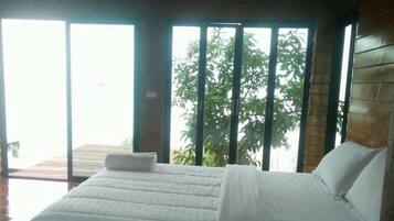 Una cama grande con cabecera de madera, una colcha blanca y una almohada.