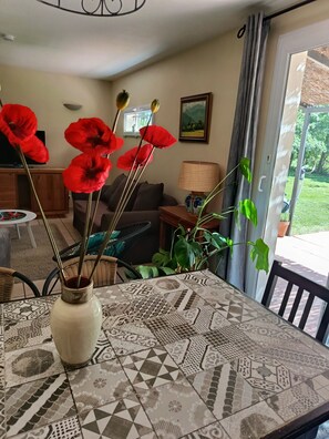 A living room with a patterned table, a sofa, a TV, and a window with curtains.