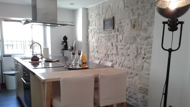 Une cuisine moderne dotée d’un îlot central, de tabourets de bar, d’un mur en pierre et d’un lampadaire.
