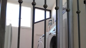 Une buanderie équipée d’un lave-linge et d’un sèche-linge, d’un radiateur et d’une fenêtre.