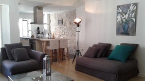 Un salon moderne comprenant un canapé, une table basse et un coin repas avec un mur en pierre et un luminaire suspendu.