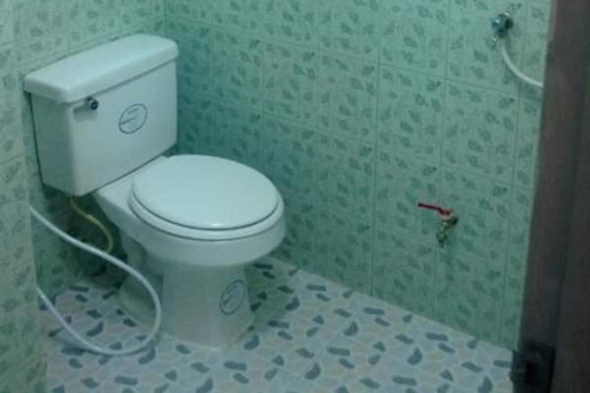 A small bathroom with a toilet, a shower, and patterned walls.