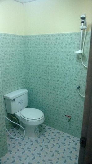 A small bathroom with a toilet, a shower, and patterned walls. - The Room Phatthalung (Phatthalung)