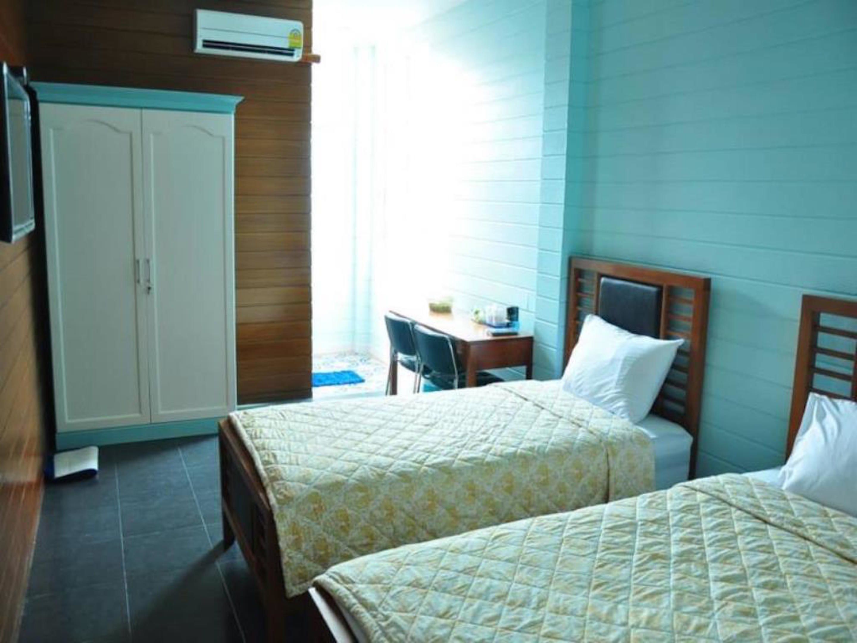 Habitación de hotel con dos camas, un escritorio y un armario.