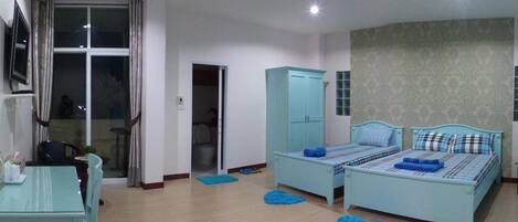 A bedroom with two beds, a desk, and a wardrobe.