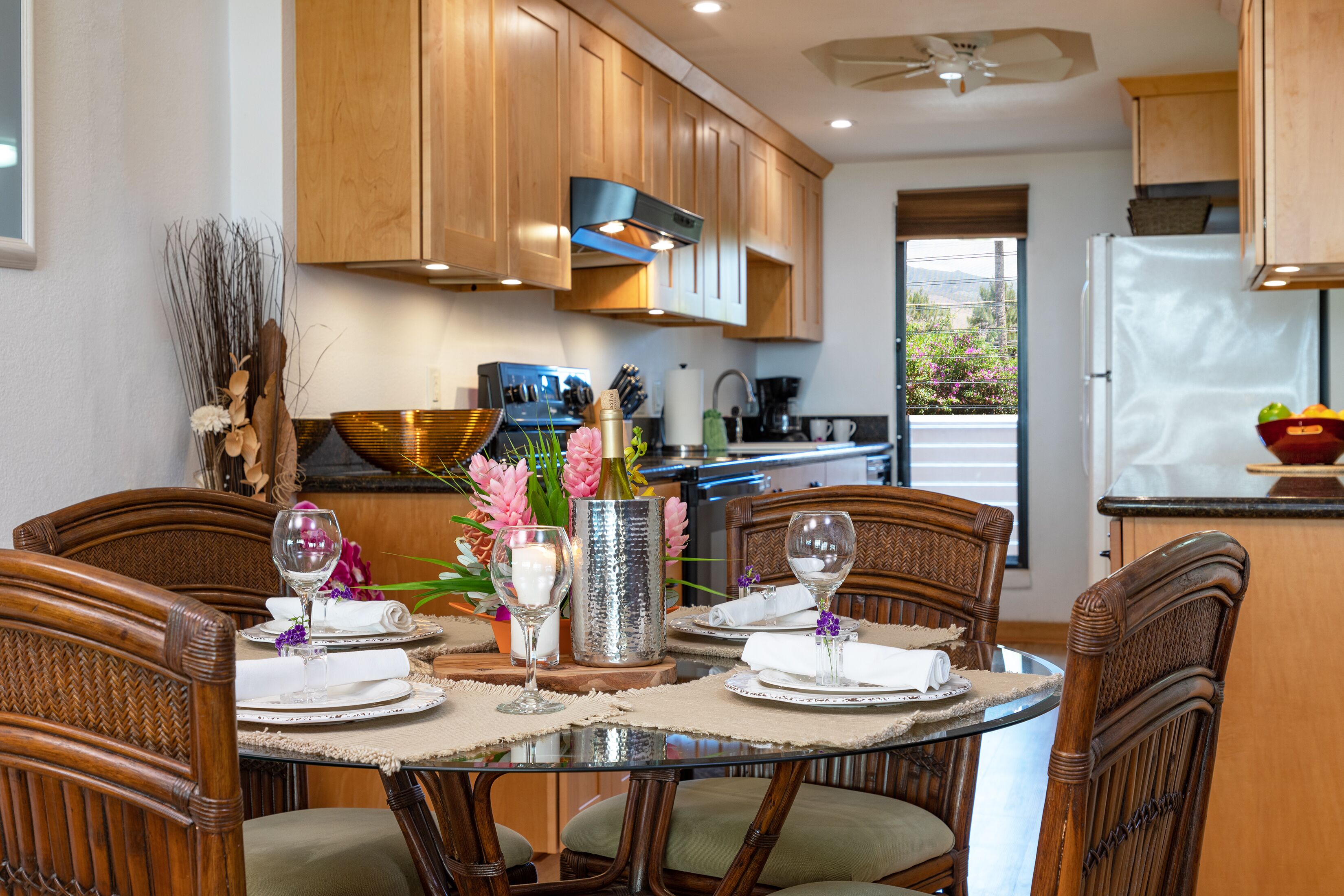 A dining area with a round table set for four, surrounded by wooden chairs.