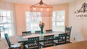 A dining area with a wooden table and chairs, a vase with flowers, and a chandelier.