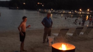 A beach scene with a fire pit and people. - Rumbling Bald Resort/Lake Lure/ Small Fee for Golf Cart.  Low cleaning fees. (Lake Lure)