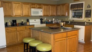 A kitchen with wooden cabinets, a central island with stools, a microwave, and a window with a view. - Rumbling Bald Resort/Lake Lure/ Small Fee for Golf Cart.  Low cleaning fees. (Lake Lure)