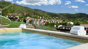 A swimming pool with a view of a mountainous landscape and buildings in the background. - Penthouse Ski-In Ski-Out Above Sheraton 1bd 1.5ba (Steamboat Springs)