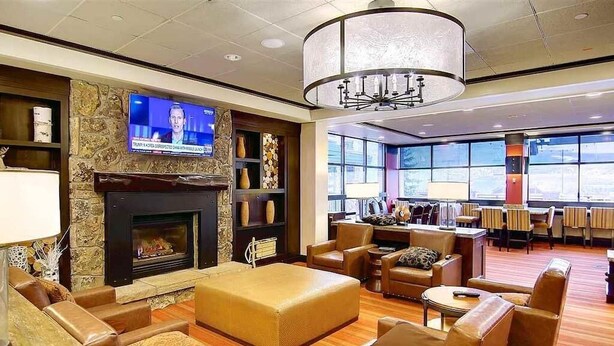 A spacious lobby with leather seating, a fireplace, a television, and large windows offering a view. - Penthouse Ski-In Ski-Out Above Sheraton 1bd 1.5ba (Steamboat Springs)
