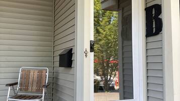 A covered porch with a metal chair, a mailbox, and a 'No Smoking' sign.