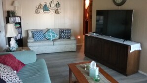 A living room with a sofa, a coffee table, a TV, and a wall clock. - Family getaway, Pet Friendly, Snowbirds, Weekend Warriors,  Welcome  (Bullhead City)