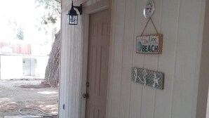 A covered porch with a door, a wall-mounted clock, and a 'Live Beach' sign. - Family getaway, Pet Friendly, Snowbirds, Weekend Warriors,  Welcome  (Bullhead City)