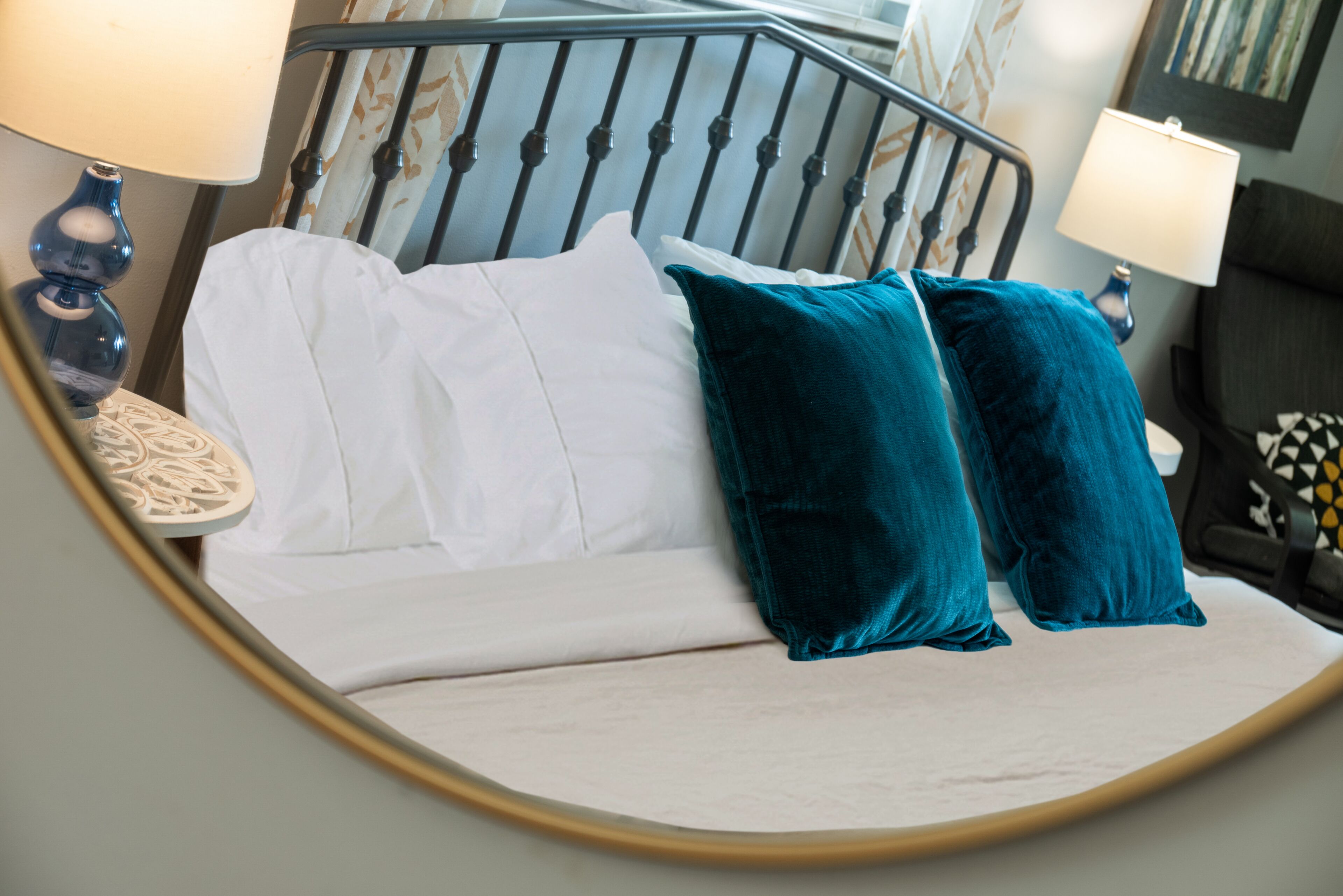 A bed with white and teal pillows, a bedside lamp, and a decorative wall.