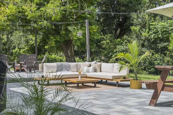 An outdoor seating area with a sofa, chairs, and a wooden table. - A Home Where Eclectic Luxury Meets Affordability (Altamonte Springs)