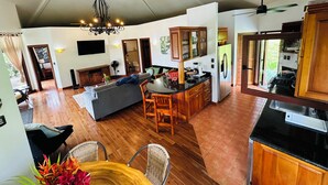 A spacious living area with a dining table, sofa, and kitchen with wooden cabinets and a refrigerator.