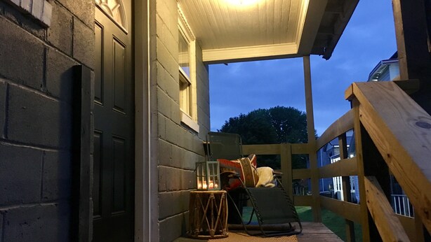 Eine überdachte Veranda mit Holzbalkon, einer Bank und einer Laterne.