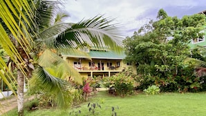 Un bâtiment à deux étages surmonté d’un toit végétalisé, entouré d’une végétation luxuriante et d’une pelouse bien entretenue.