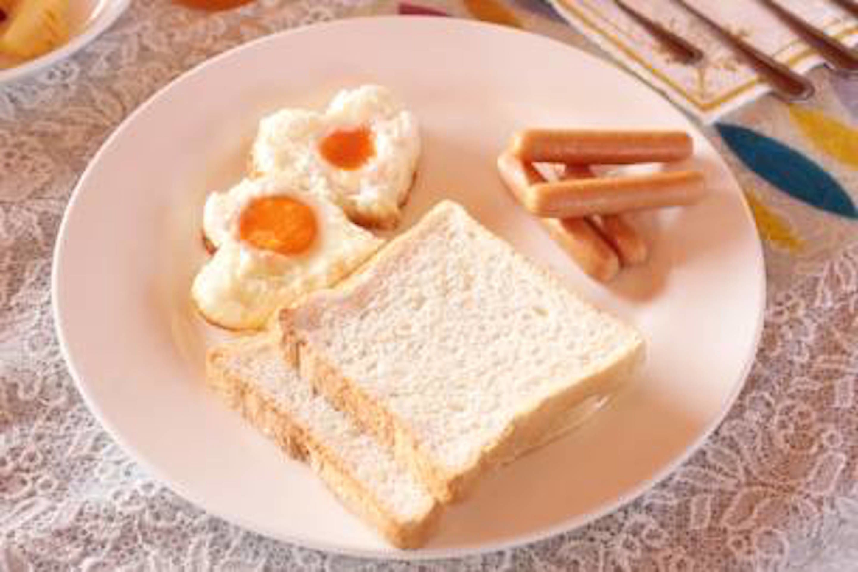 A plate with two slices of white bread, two fried eggs, and a few pieces of toast.