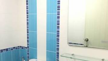 A bathroom with a toilet, sink, and mirror.