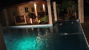 A nighttime view of a swimming pool with a house in the background. - Rimlay Park Resort (Phatthalung)