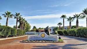 A sign for Las Palmas Resort Condominiums with a paved entrance and palm trees. - Extra large one bedroom with access to the Las palmas Resort  pools. (Saint George)