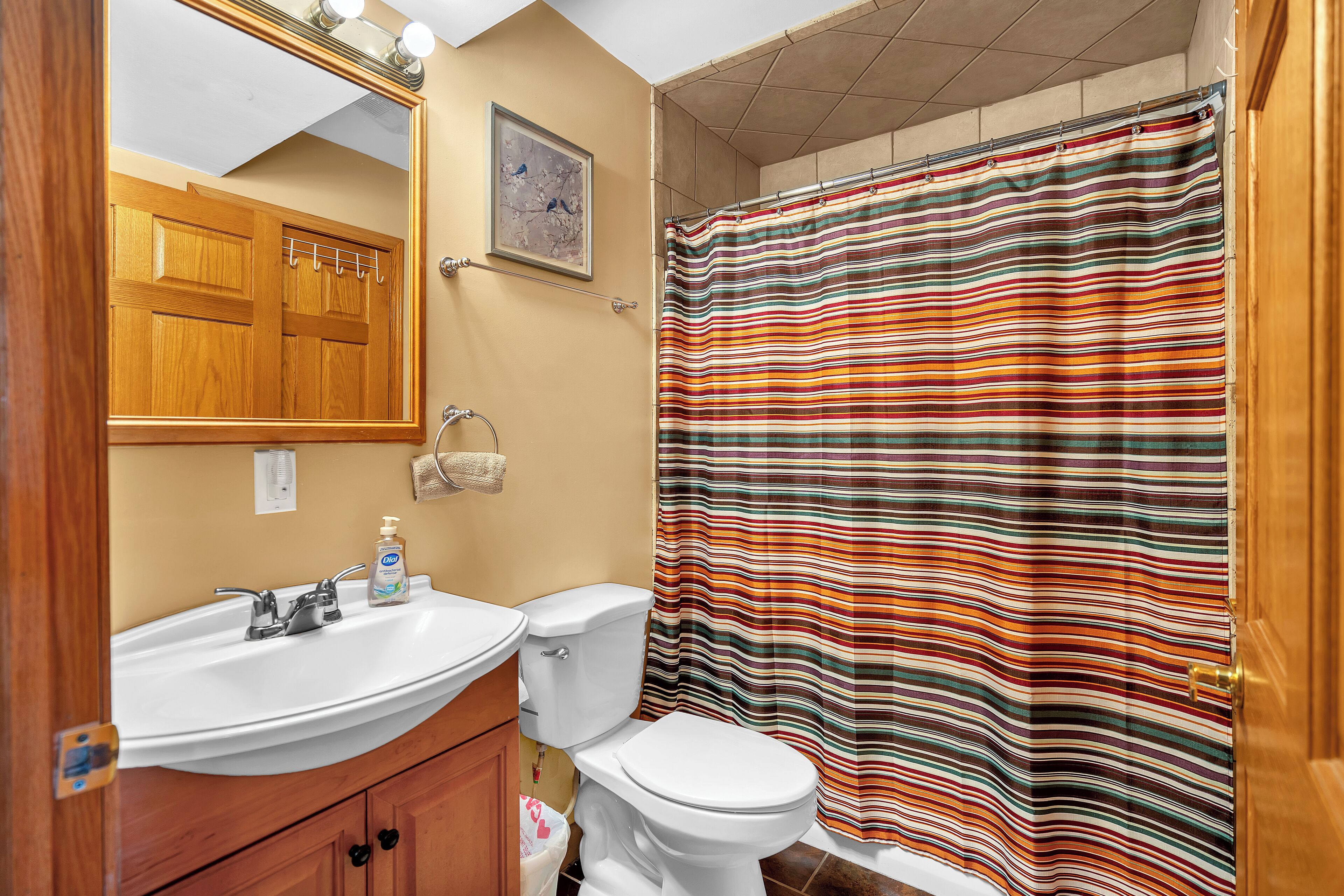 A bathroom with a wooden vanity, white sink, and toilet.