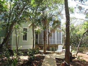 A house with a deck, surrounded by trees and a garden.