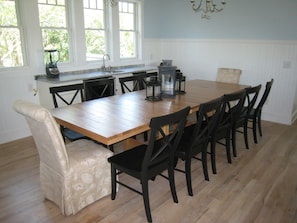A dining area with a wooden table and black chairs, a kitchen with a sink and stove, and a chandelier.