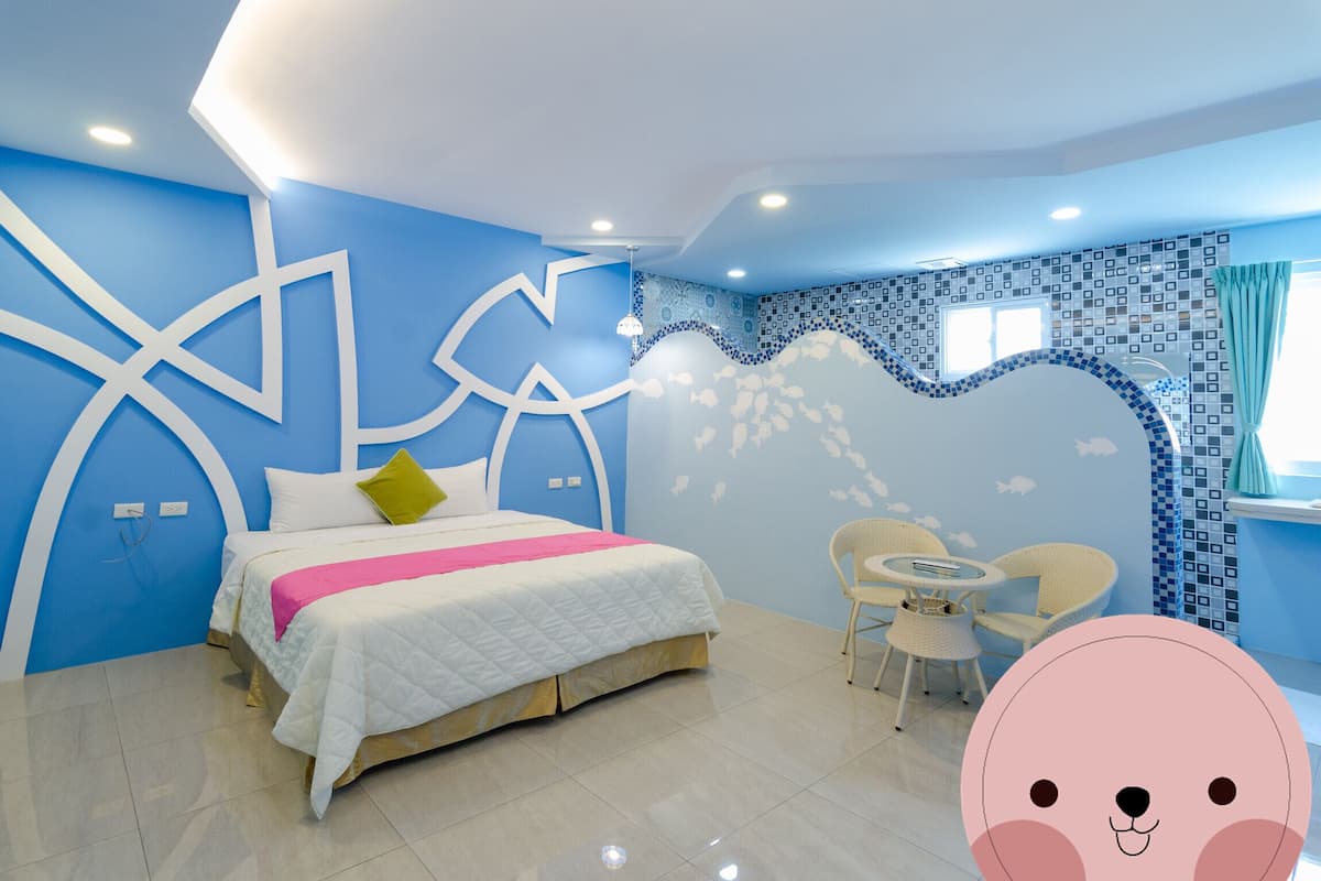 A modern bedroom with a bed, a small table, and chairs.