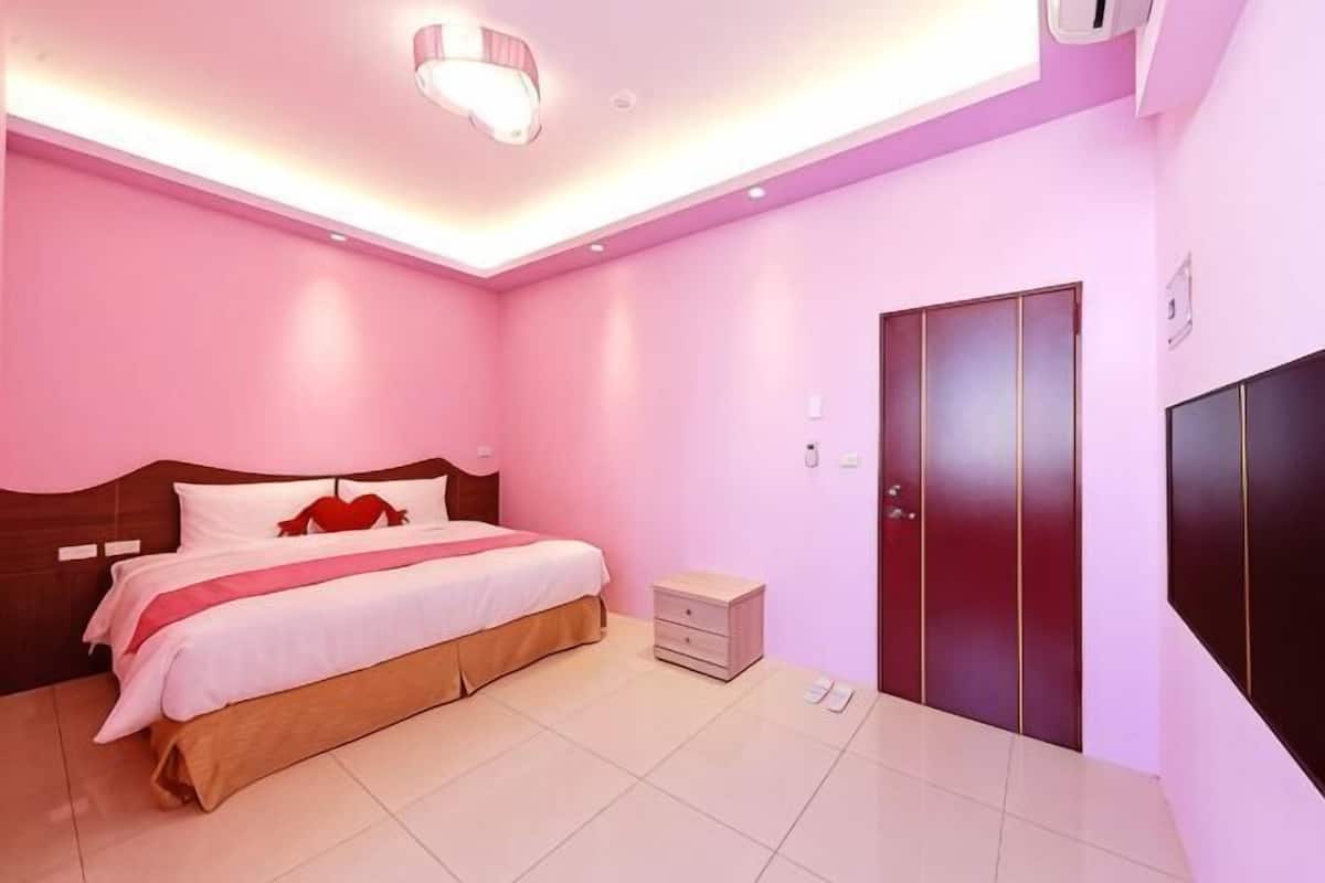 A bedroom with a bed, bedside table, wardrobe, and a ceiling light fixture.