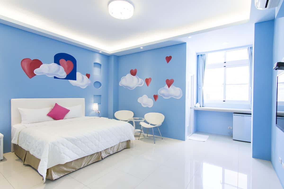 A modern bedroom with a large bed, a desk, and chairs.