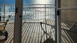 Un balcon avec vue sur l’océan, une chaise et une table.