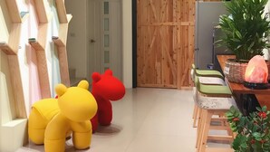 A modern living room with a wooden wall unit, a large wooden door, a dining area with a table and chairs, and a television. - Happy Fat B&B (Taitung)
