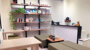 A modern, well-lit room with a wooden desk, green cushioned seating, and shelves with books and decorative items. - Happy Fat B&B (Taitung)