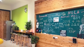 A classroom with a chalkboard, wooden desks, chairs, and a refrigerator. - Happy Fat B&B (Taitung)